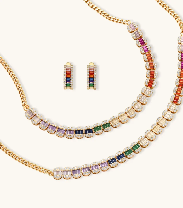Gold-plated jewelry set featuring rainbow baguette-cut cubic zirconia stones in geometric design on cream background