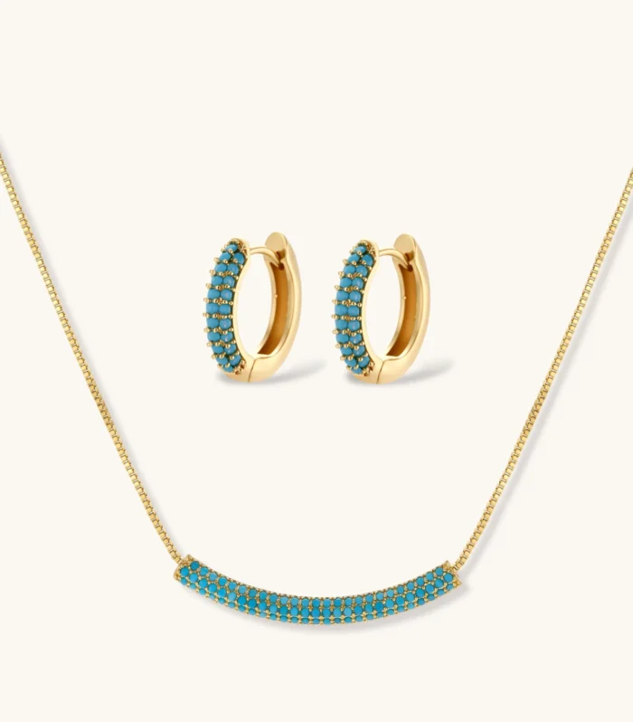 Gold-plated curved necklace and hoop earrings with turquoise cubic zirconia stones on white background.