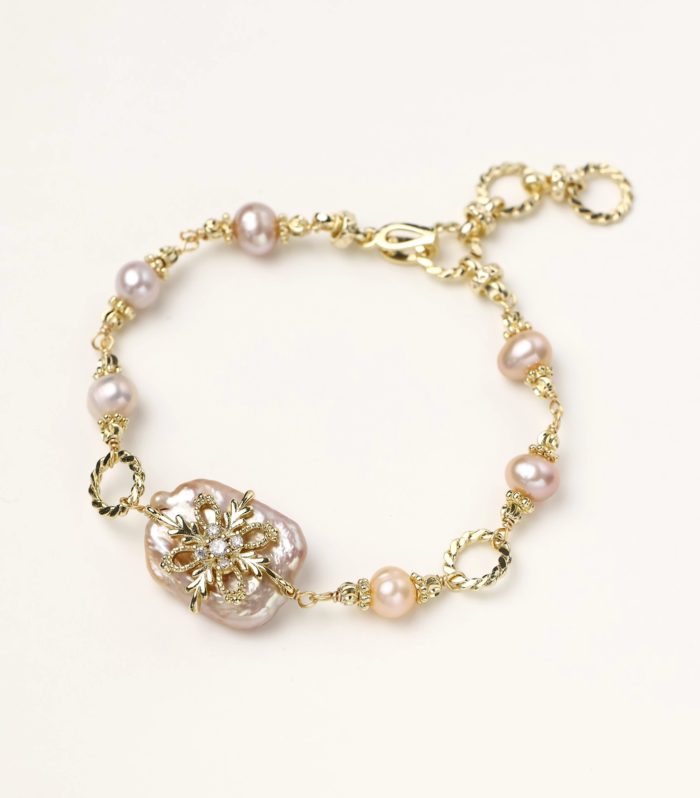 Gold-plated bracelet with pink baroque pearl centerpiece, floral connector, and freshwater pearls