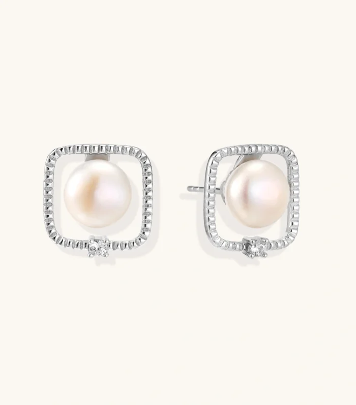 Rhodium-plated silver stud earrings with cushion frame, centered freshwater pearl, and tiny crystal accent
