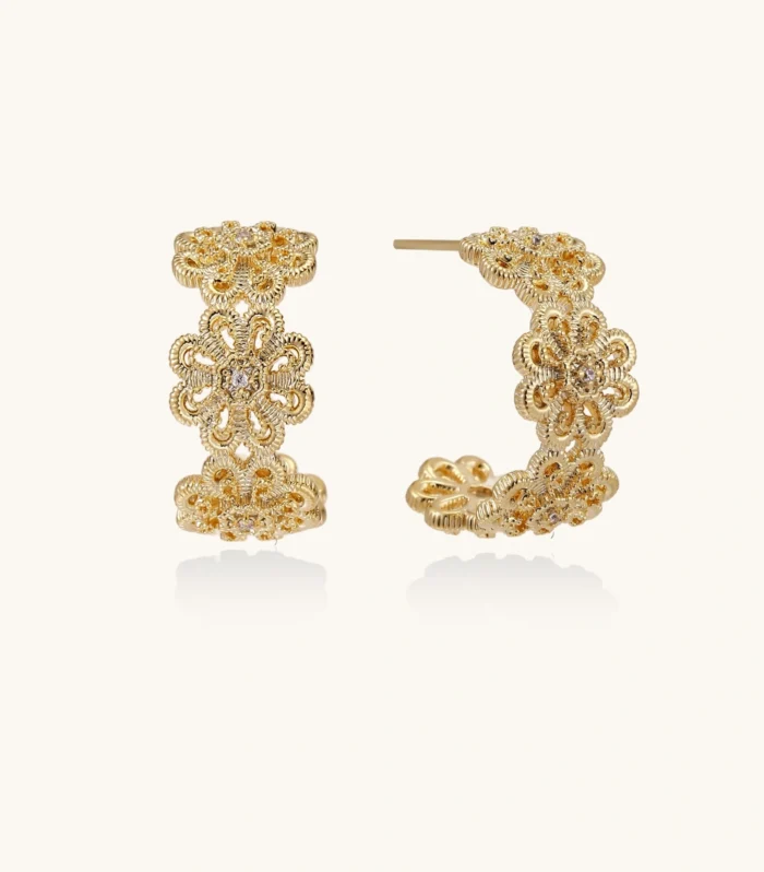Gold hoop earrings with intricate three-dimensional floral filigree pattern in 14K gold plated brass on cream background
