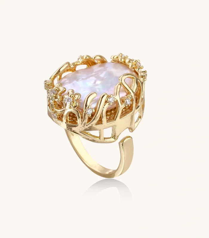 Gold filigree crown ring cradling an iridescent baroque freshwater pearl with crystal accents on white background