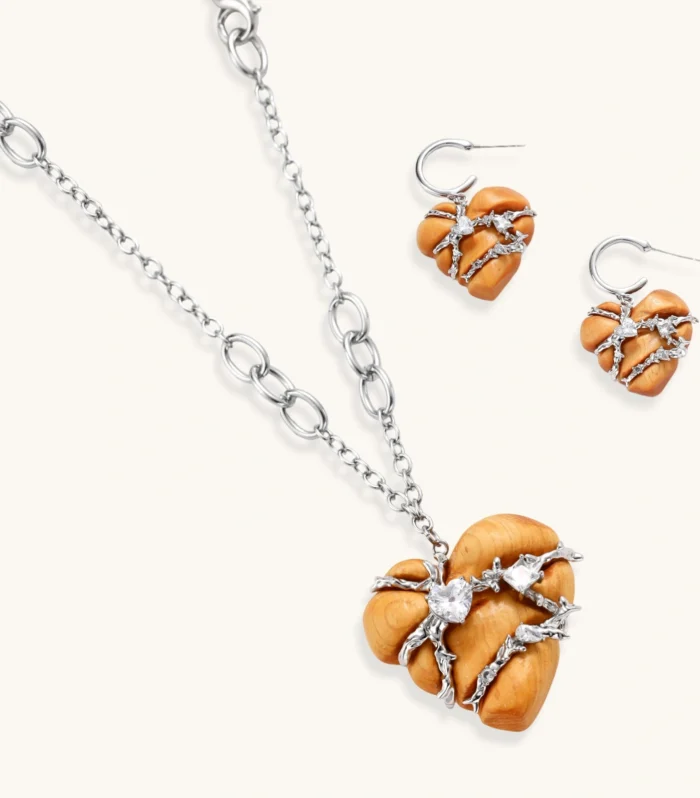Heart-shaped eco-brass and wood jewelry set with silver wire detailing and crystal accents on cream background.