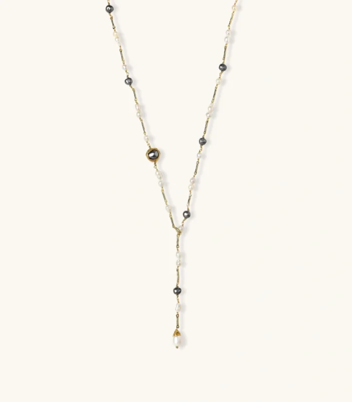 Y-shaped gold-plated necklace with white and gray freshwater pearls on cream background, showing adjustable drop design.